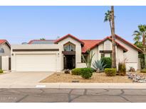 Single-story home with red tile roof, desert landscaping, and a two-car garage at 11085 E Becker E Ln, Scottsdale, AZ 85259