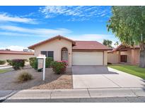 Tan stucco house with red tile roof, attached garage, and landscaping at 5203 E Saguaro Cir, Phoenix, AZ 85044