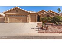 Tan house with two-car garage and nicely landscaped front yard at 26219 S Flame Tree Dr, Sun Lakes, AZ 85248