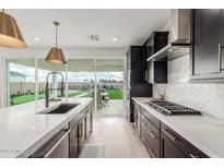 Modern kitchen features dark cabinetry, white quartz countertops, and a view of the backyard at 17329 W Gretna St, Surprise, AZ 85388