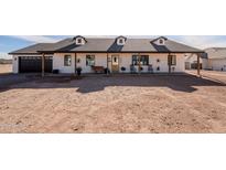 White farmhouse exterior with a covered porch, dark garage door, and landscaping at 1187 W Lucky Ln, San Tan Valley, AZ 85144