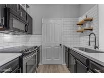 Modern galley kitchen, featuring black cabinetry, white subway tile, and stainless steel appliances at 16013 S Desert Foothills Pkwy # 1035, Phoenix, AZ 85048