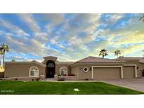 Single-story home with a tile roof, landscaped lawn, and a three-car garage at 8689 E Windrose Dr, Scottsdale, AZ 85260
