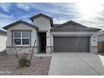 New single-story home with gray exterior, stone accents, and a two-car garage at 10541 W Sonrisas St, Tolleson, AZ 85353