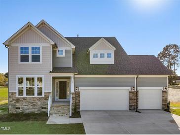 Two-story home with gray siding, stone accents, and a three-car garage at 17 Shelby Meadow Ln, Angier, NC 27501