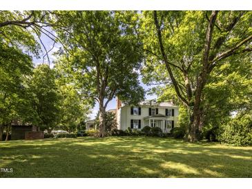 White farmhouse with lush green landscape at 6720 Mebane Oaks Rd, Mebane, NC 27302
