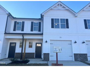 White two-story townhome with a two-car garage and landscaping at 97 Calluna Dr, Clayton, NC 27520