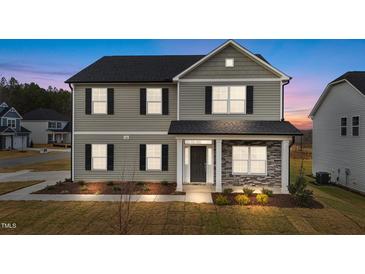 Two-story home with gray siding, stone accents, and a covered front porch at twilight at 535 Husketh Rd, Youngsville, NC 27596