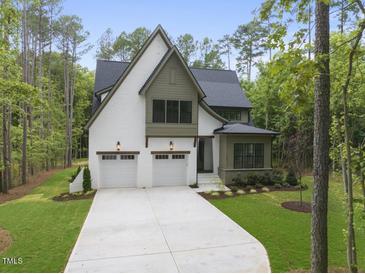 Two-story house with green and white exterior, two-car garage, and landscaped yard at 13541 Old Creedmoor Rd, Wake Forest, NC 27587