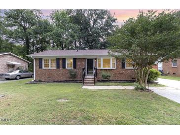 Brick ranch house with landscaped lawn, showcasing a welcoming front porch at 2912 Omah St, Durham, NC 27705