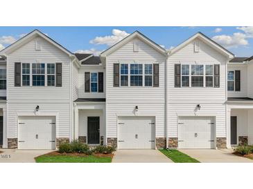 Three-unit townhome building, white siding, two-car garages, stone accents at 463 David Hill Dr, Sanford, NC 27330