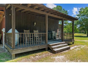 Rustic front porch with rocking chairs, offering a relaxing view of the property at 113 Amelia Ln, Holly Springs, NC 27540