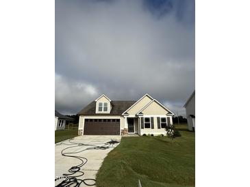 Beige house with brown accents, double garage, and green lawn at 32 Scotties Ridge Dr, Princeton, NC 27569