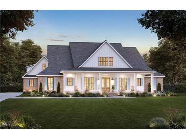 Two story farmhouse with front porch, brick accents, and landscaped lawn at 6604 Deermont Ct, Gibsonville, NC 27249