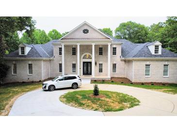Two-story brick home with circular driveway, landscaping, and a white SUV at 5200 Blue Stem Ct, Raleigh, NC 27606
