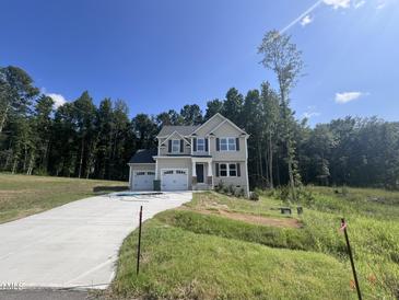 Two-story house with light beige siding, two-car garage, and a landscaped yard at 321 Constellation Ct, Benson, NC 27504