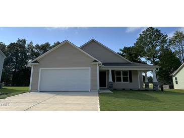 Beige house with white garage door and stone accents at 32 Oakfield Trace Dr, Four Oaks, NC 27524