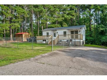 Single-story home with deck, fenced yard, and storage shed at 113 Winnebago Loop, Louisburg, NC 27549