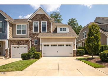 Two-story townhome with stone and siding accents, two-car garage, and landscaped front yard at 622 Chronicle Dr, Cary, NC 27513