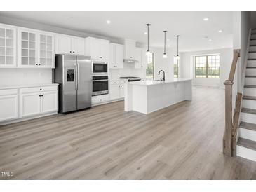 Modern kitchen with white cabinets, island, and stainless steel appliances at 1226 Helms St, Durham, NC 27713