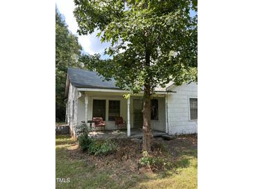 A white, ranch-style house with a covered porch and mature trees in the front yard at 4285 Belltown Rd, Oxford, NC 27565