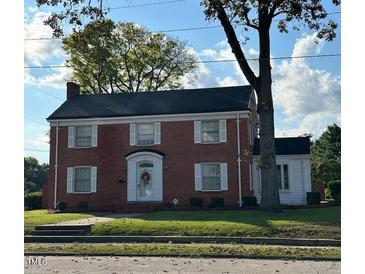Brick two-story house with a large front yard and mature trees at 110 S Layton Avenue, Dunn, NC 28334