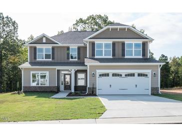 Two-story house with a large white garage door and landscaping at 168 Newport Lndg, Garner, NC 27529