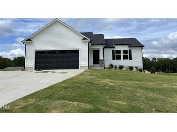 White house with black garage doors and landscaped lawn at 749 Sherrill Farm Dr, Benson, NC 27504