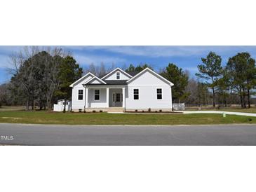 White farmhouse exterior with a landscaped lawn at 15 Bella Ln, Zebulon, NC 27597