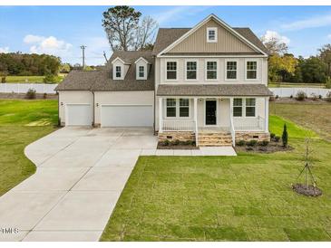 Two story home with three car garage, stone accents, and front porch at 122 Whimbrel Ct, Lillington, NC 27546