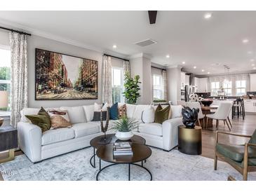 Open living room showcasing a sectional sofa, coffee table, and adjacent kitchen at 1170 Holding Village Way, Wake Forest, NC 27587