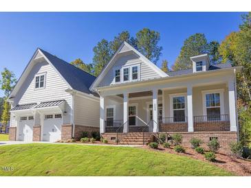 Two-story home with gray siding, brick accents, and a three-car garage at 143 Traceway N, Sanford, NC 27332