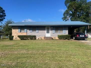 Ranch-style home with a blue metal roof and landscaped yard at 108 Gulf Dr, Dunn, NC 28334