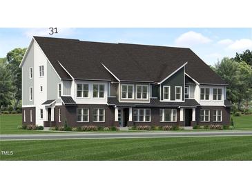 Modern three-story townhome with gray and brick exterior, and a grassy lawn at 2411 Adrift Rd, Fuquay Varina, NC 27526