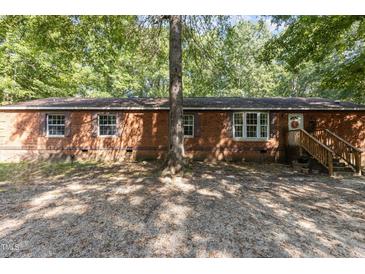 Brick ranch house with a wooden front porch and a gravel driveway at 118 W Silver Belle Dr, Zebulon, NC 27597