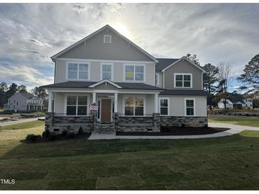 Two story house with gray siding, stone accents, and a large front yard at 23 Quail Pt Cir, Clayton, NC 27520