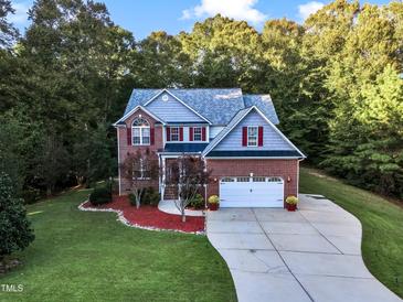 Two story home with brick and gray siding, two car garage, and landscaping at 319 River Knoll Dr, Clayton, NC 27527