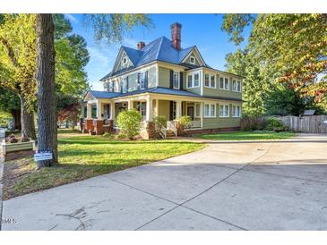 Large two-story house with a wrap-around porch and brick accents at 26 Oak St, Roxboro, NC 27573