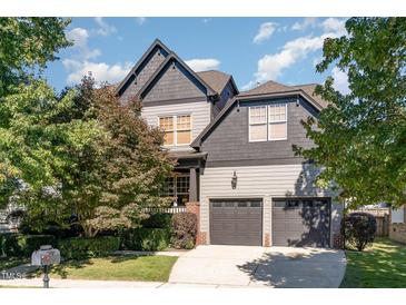 Two-story house with dark gray and beige exterior, two-car garage, and well-manicured lawn at 3009 Gentle Breezes Ln, Raleigh, NC 27614