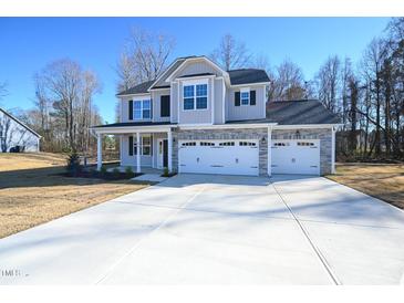 Two-story house with gray siding, stone accents, and a three-car garage at 49 Abingdon Farms Dr, Selma, NC 27576