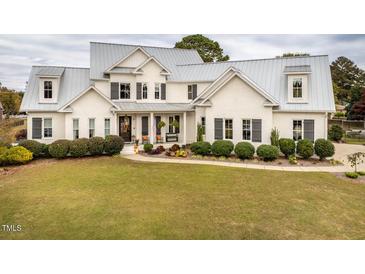 Charming two-story home with a metal roof, white brick exterior, and a welcoming front yard at 105 Creech Cir, Four Oaks, NC 27524