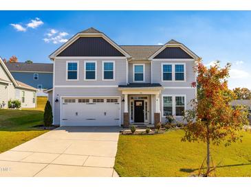 Two-story home with gray siding, a three-car garage, and a well-maintained lawn at 52 E Piston Pt, Clayton, NC 27520