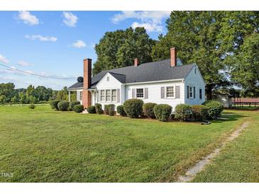 White house with brick chimney, surrounded by lush green lawn at 9847 Snow Camp Rd, Snow Camp, NC 27349