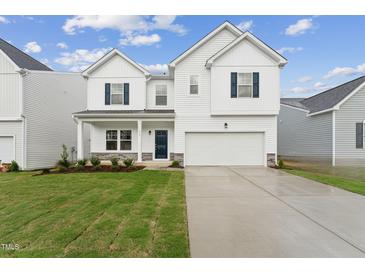 Two-story white house with gray door, brick steps, and a two-car garage at 6525 Winter Spring Dr, Wake Forest, NC 27587