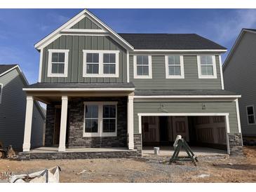 Two-story home with gray siding, stone accents, and a covered front porch at 64 Charming Ct, Fuquay Varina, NC 27526