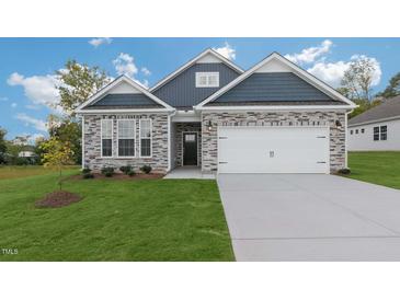 Attractive two-story home with stone and blue siding, a two-car garage, and a well-manicured lawn at 1680 Abberly Pl, Graham, NC 27253