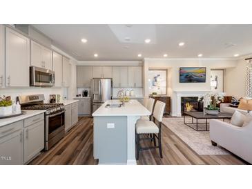 Open concept kitchen features island, stainless steel appliances, and white cabinetry at 1819 Barrett Run Trl # 336, Apex, NC 27502