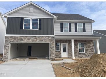 Two-story home with stone and gray siding, two-car garage, and landscaping at 517 Southwick Pl, Mebane, NC 27302