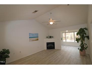 Bright living room features a corner fireplace, vaulted ceilings and laminate flooring at 11331 Involute Pl # 100, Raleigh, NC 27617