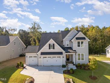 Two-story home with gray siding, three-car garage, and landscaped lawn at 323 W Amber Oak Dr, Selma, NC 27576